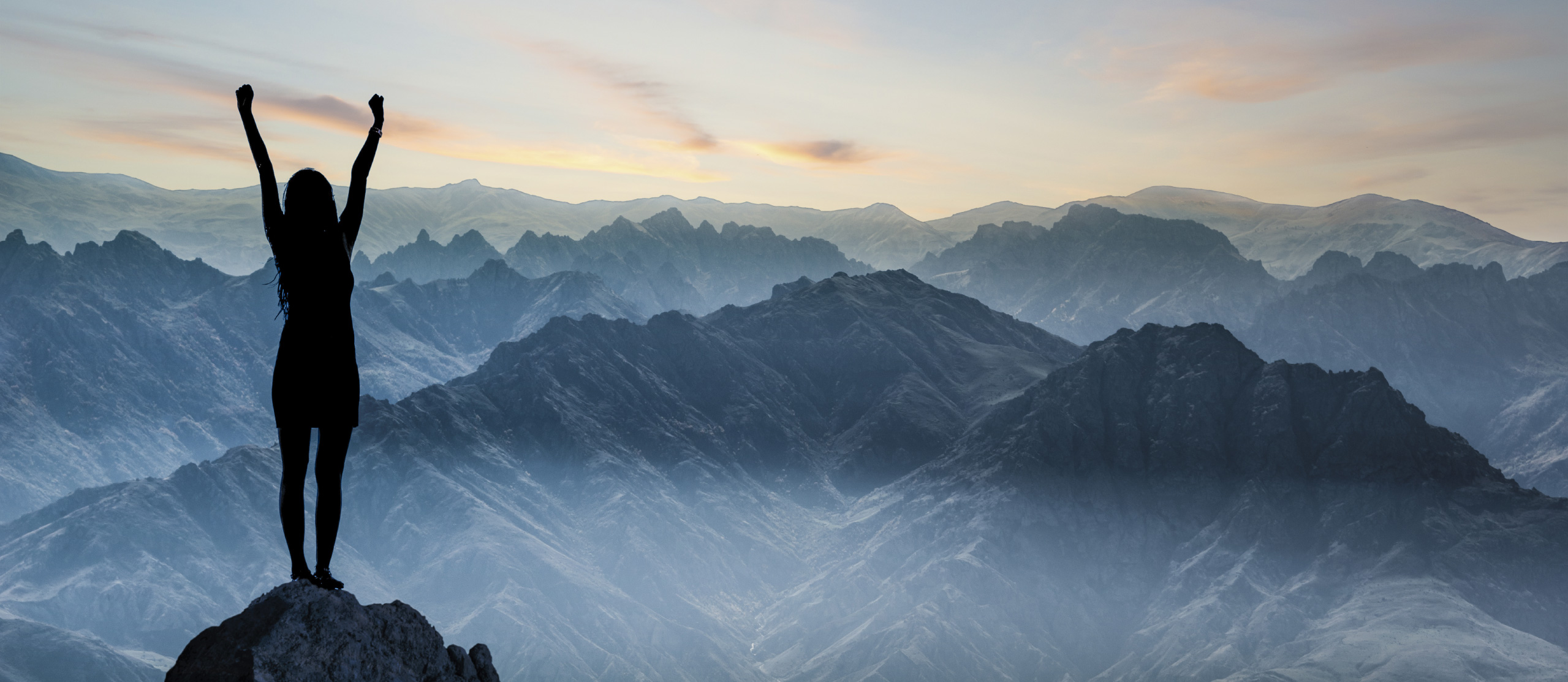 Ragazza sulla vetta di una montagna con le bracia in alto